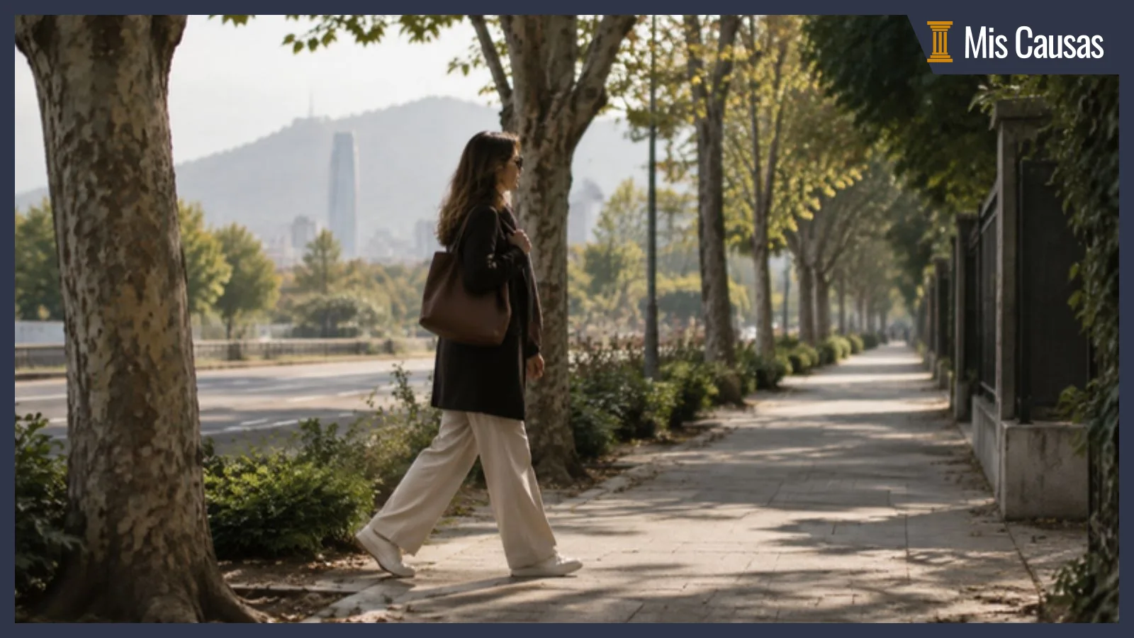 Mujer de perfil caminando por una vereda arbolada de Santiago con un bolso al hombro, con la cordillera al fondo por la mañana